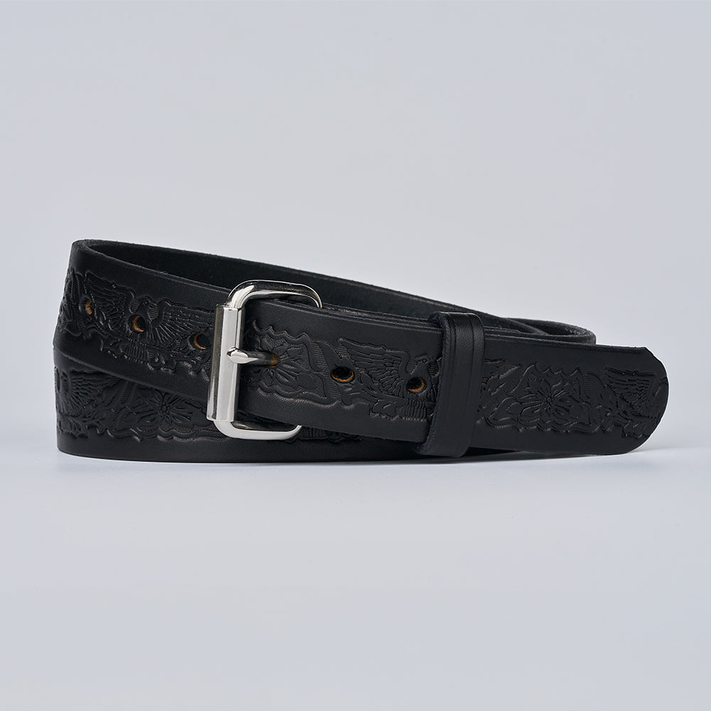 The Gunner Eagle by Hanks Belts, a black full-grain leather belt with a silver buckle and embossed patterns, is coiled on a plain light background.