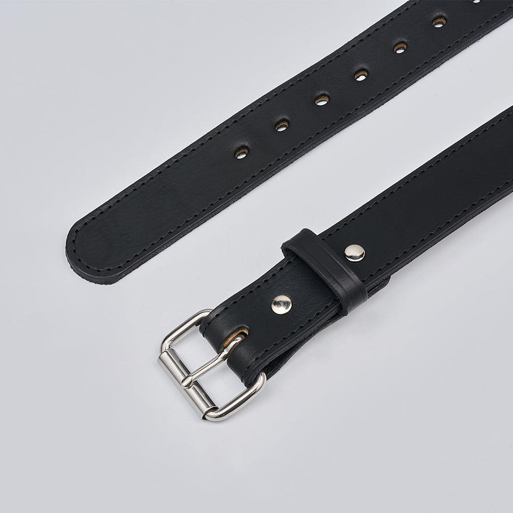 A close-up of The Gunner Stitched by Hanks Belts, a black full-grain leather belt with a silver buckle and metal rivets, shown on a light gray background. Multiple adjustment holes make it perfect as a CCW belt.