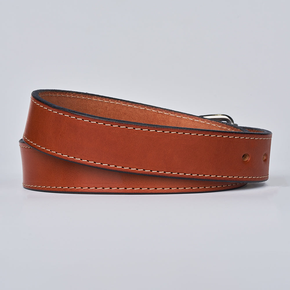 The Gunner Stitched by Hanks Belts is a brown full-grain leather belt with white edge stitching and a metal buckle, shown rolled up on a plain light background—ideal as a stylish CCW belt for everyday carry.