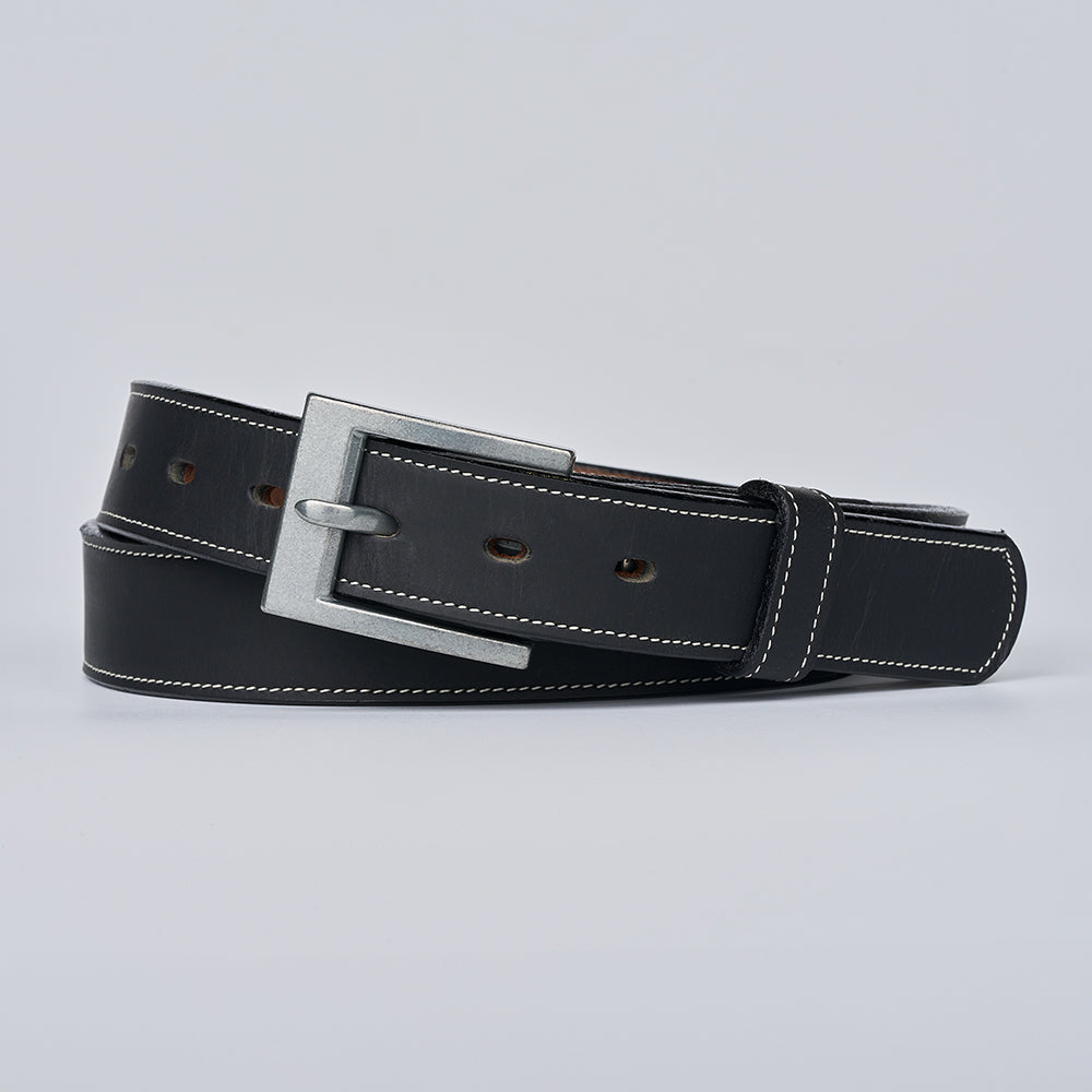 The Heritage Bison by Hanks Belts—a black bison leather belt with white stitching and a silver rectangular buckle—coiled on a light gray background, epitomizes American craftsmanship.