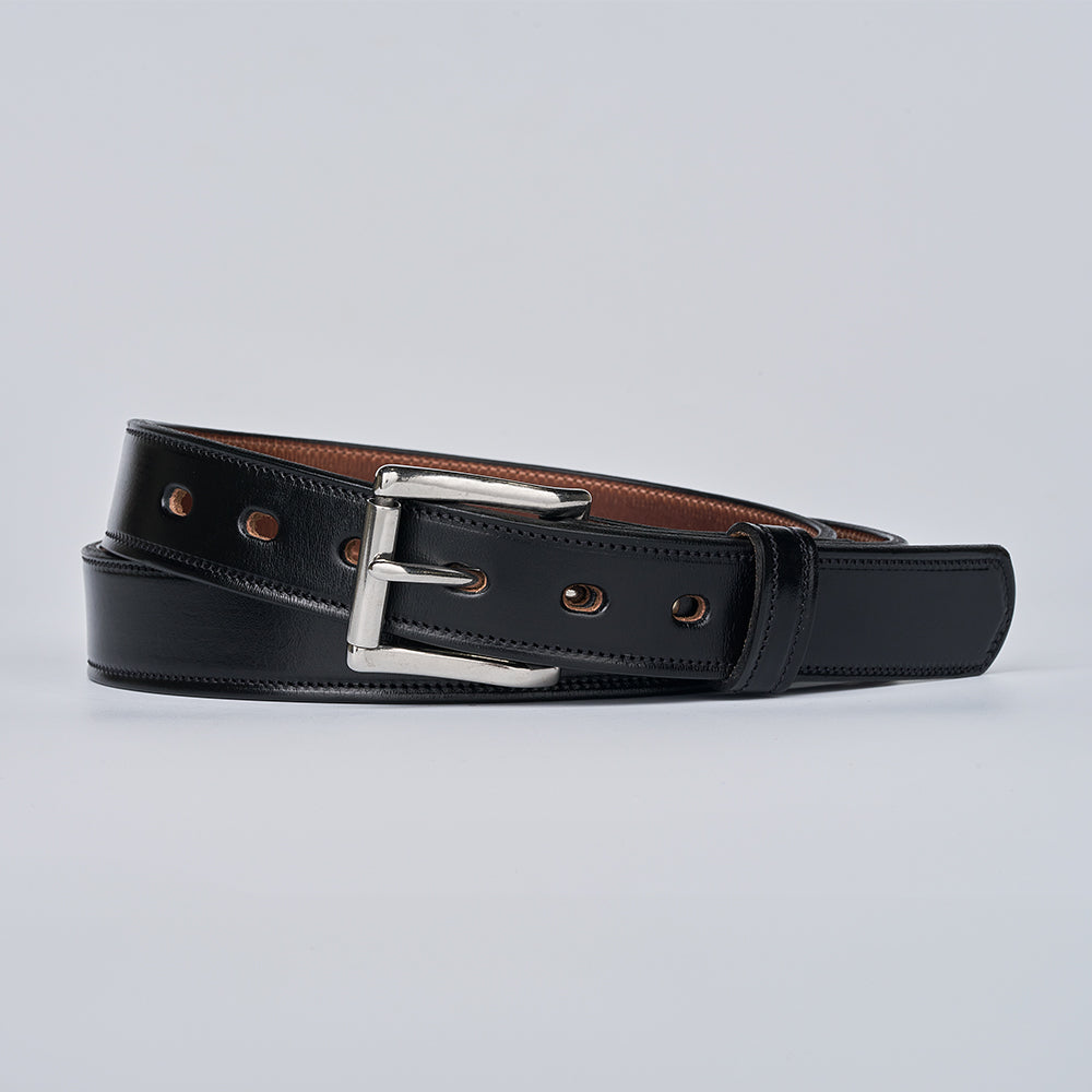 The Highland Lined by Hanks Belts is a black premium leather belt with a silver buckle, brown inner edging, and multiple holes, coiled neatly on a plain light background.