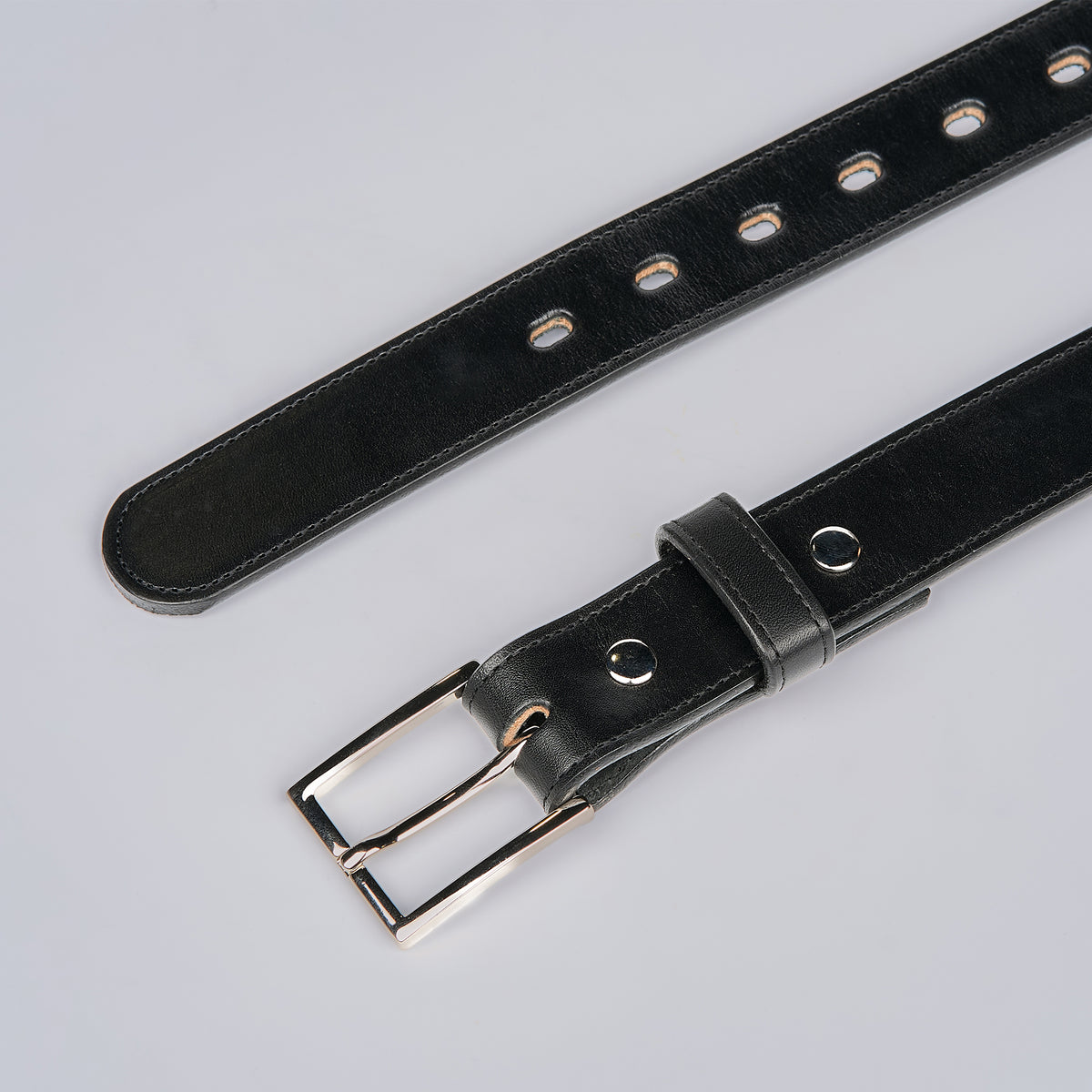 The Ledger by Hanks Belts is a men's English bridle leather belt with a silver rectangular buckle and multiple round holes, shown on a light gray background.