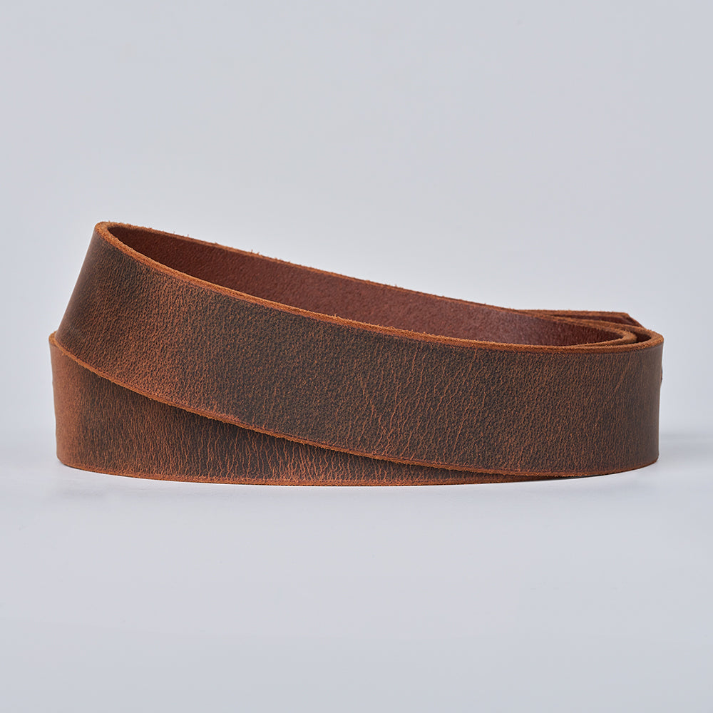 The Hanks Belts Legend Double Prong Retro Style features a coiled strip of brown full grain textured leather, showcased against a plain light gray background.