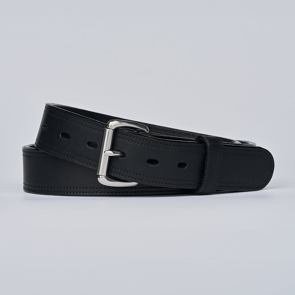 The Old World Harness by Hanks Belts is a black full-grain leather belt with a silver buckle, made from USA-tanned Hermann Oak leather, shown coiled on a plain light gray background.