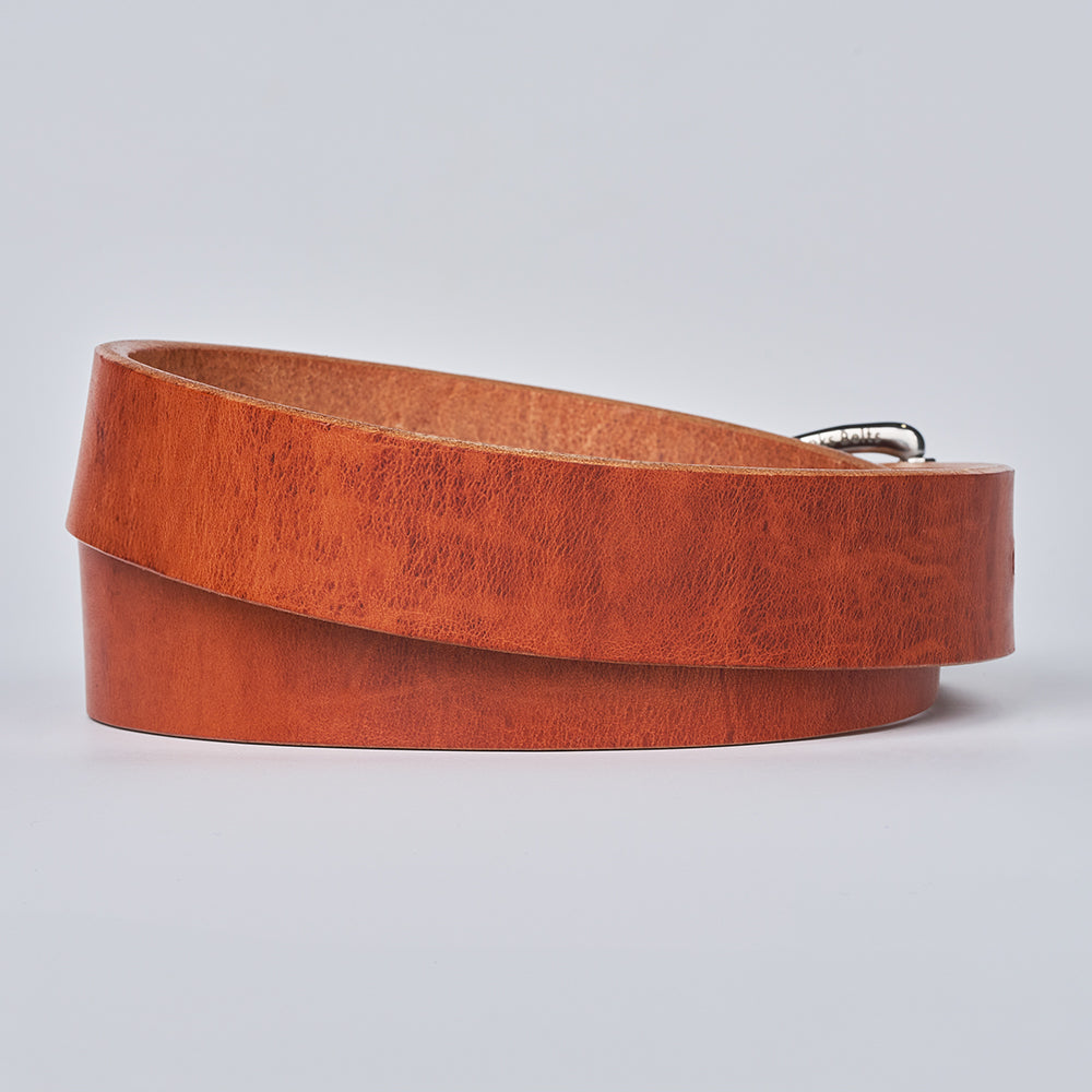 The Old World Harness by Hanks Belts is a coiled, brown full-grain leather belt with a silver buckle, expertly crafted from Hermann Oak USA-tanned leather and displayed on a plain light background.