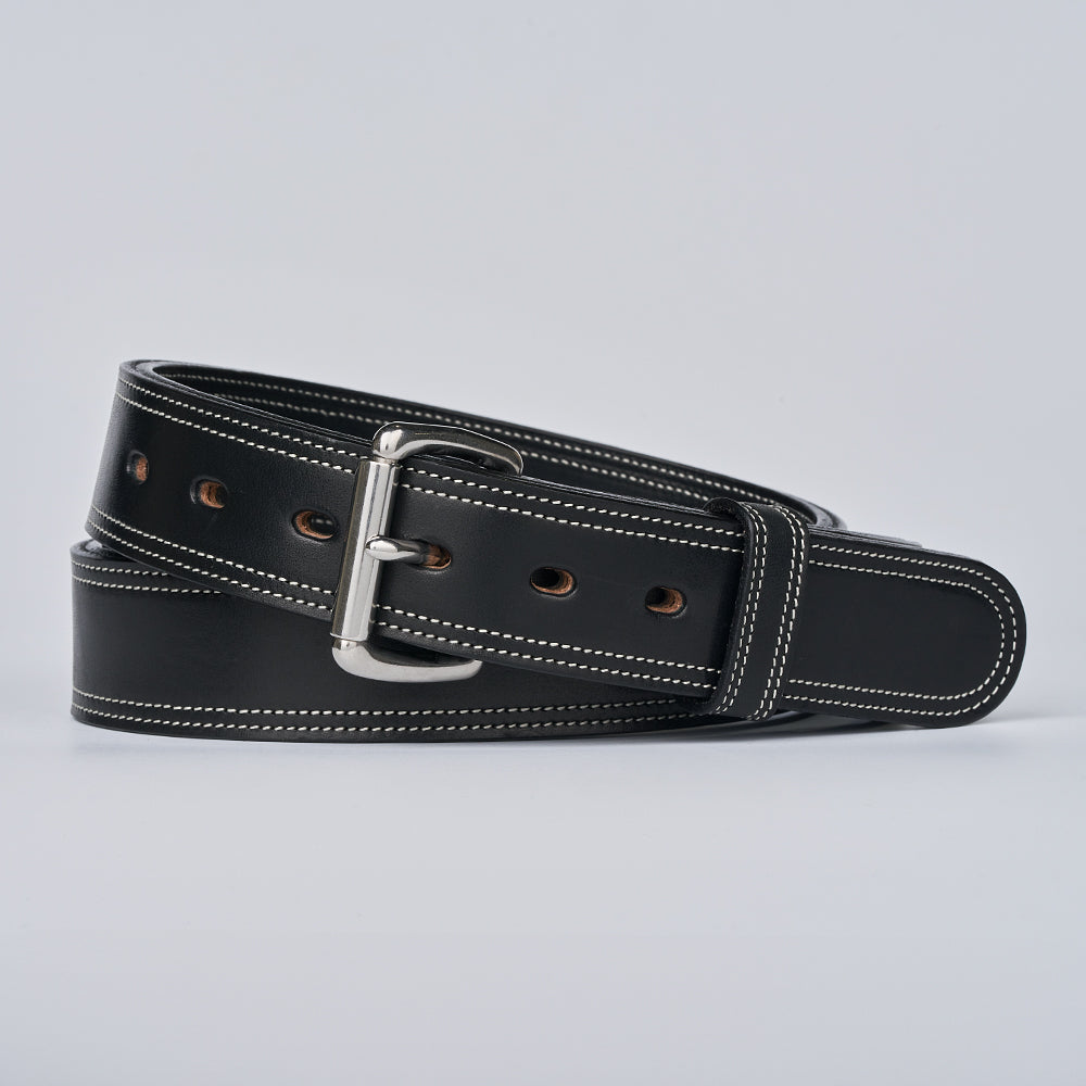 The Premier Double Layer by Hanks Belts, a black English bridle belt with white stitching and a silver buckle, is coiled neatly against a light gray background.