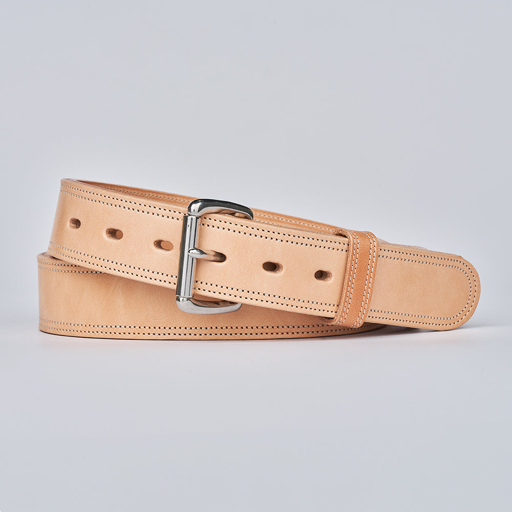 The Premier Double Layer by Hanks Belts is a tan English bridle belt with a silver buckle, crafted from vegetable-tanned leather. It has edge stitching and multiple adjustment holes, shown against a plain light gray background.