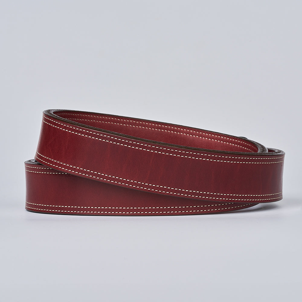 The Premier Double Layer by Hanks Belts is a coiled brown vegetable-tanned leather belt with white edge stitching, shown on a plain light gray background.