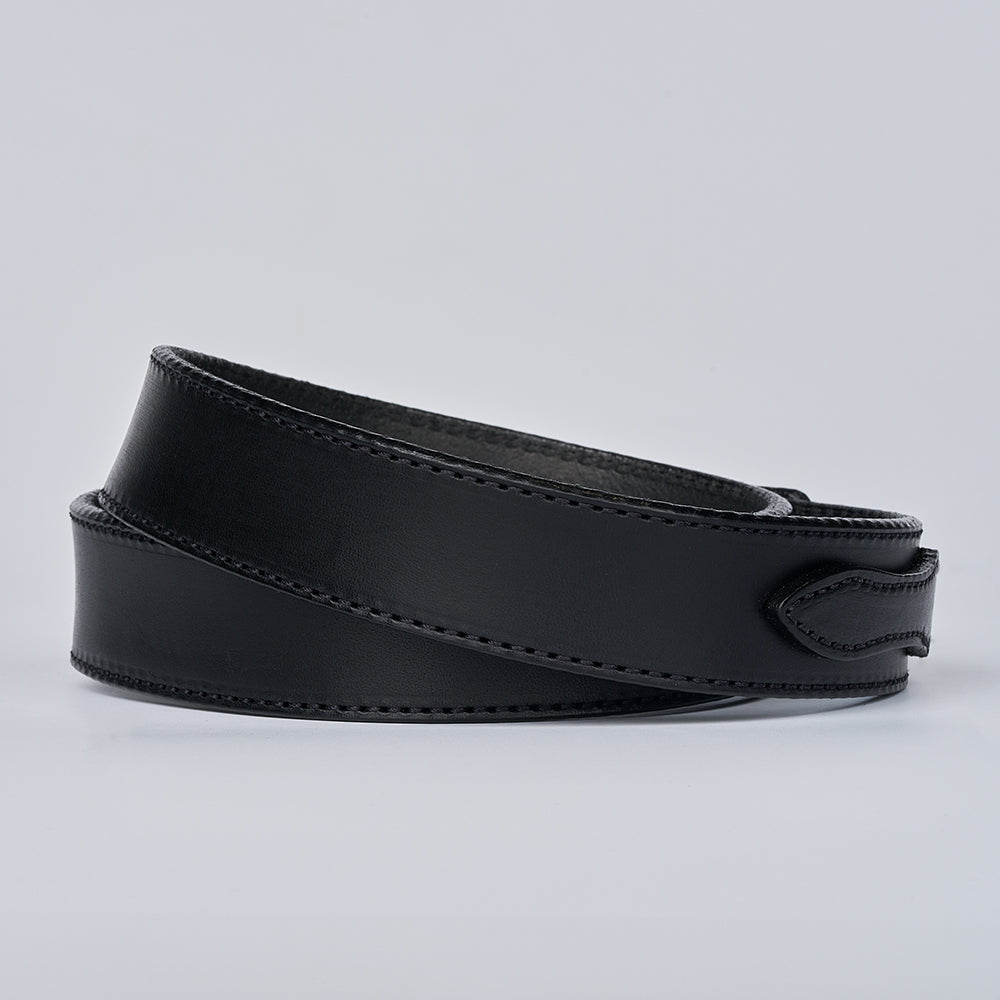 The Ranger by Hanks Belts is a full grain leather belt, coiled neatly on a plain light gray background, featuring detailed edge stitching.