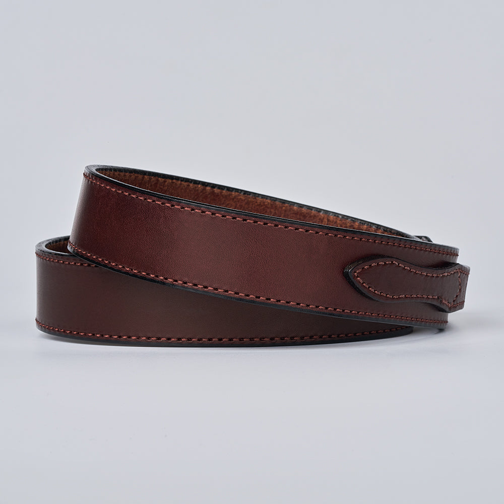 The Ranger belt by Hanks Belts is shown coiled, crafted from brown full grain leather with visible stitching, set against a plain light gray background.
