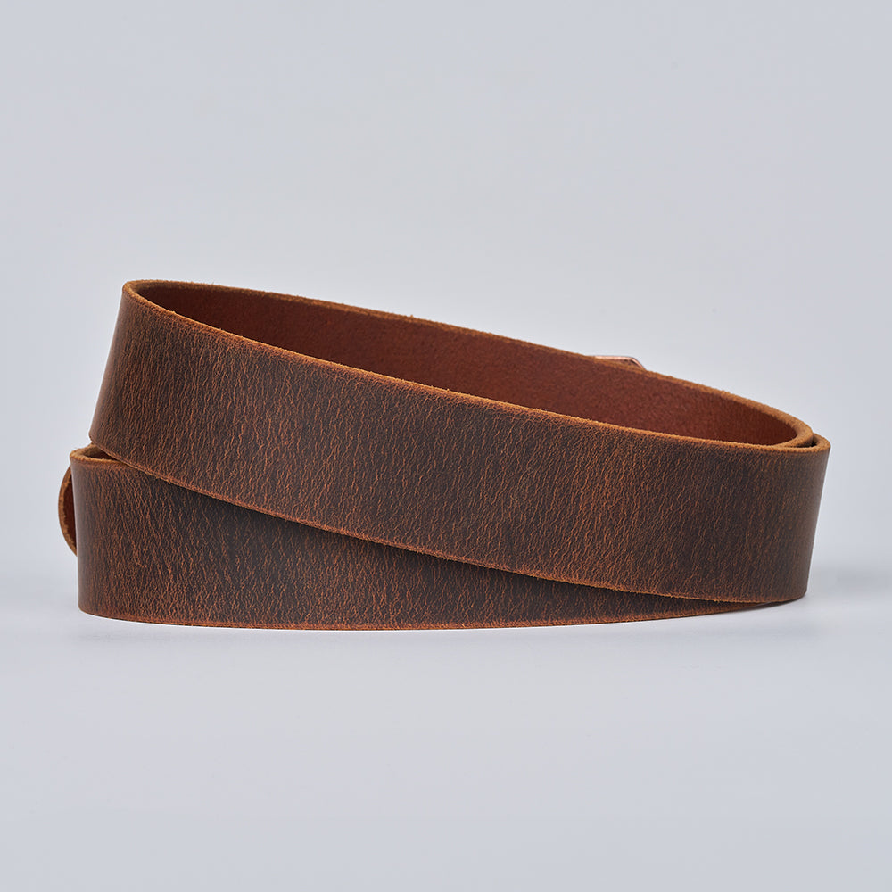 The Relic Retro Style belt by Hanks Belts, made from smooth, matte brown Water Buffalo leather, is shown rolled up on a plain light gray background.
