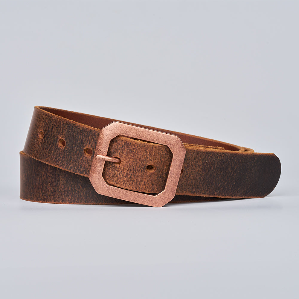 The Relic Retro Style by Hanks Belts: a brown leather belt with a geometric copper buckle, displayed coiled on a light gray background.
