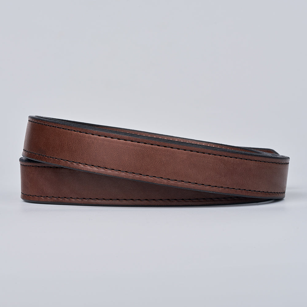 The Steel Core - 1.25&quot; by Hanks Belts: a coiled brown leather CCW belt with visible stitching, displayed without a buckle on a plain light gray background.