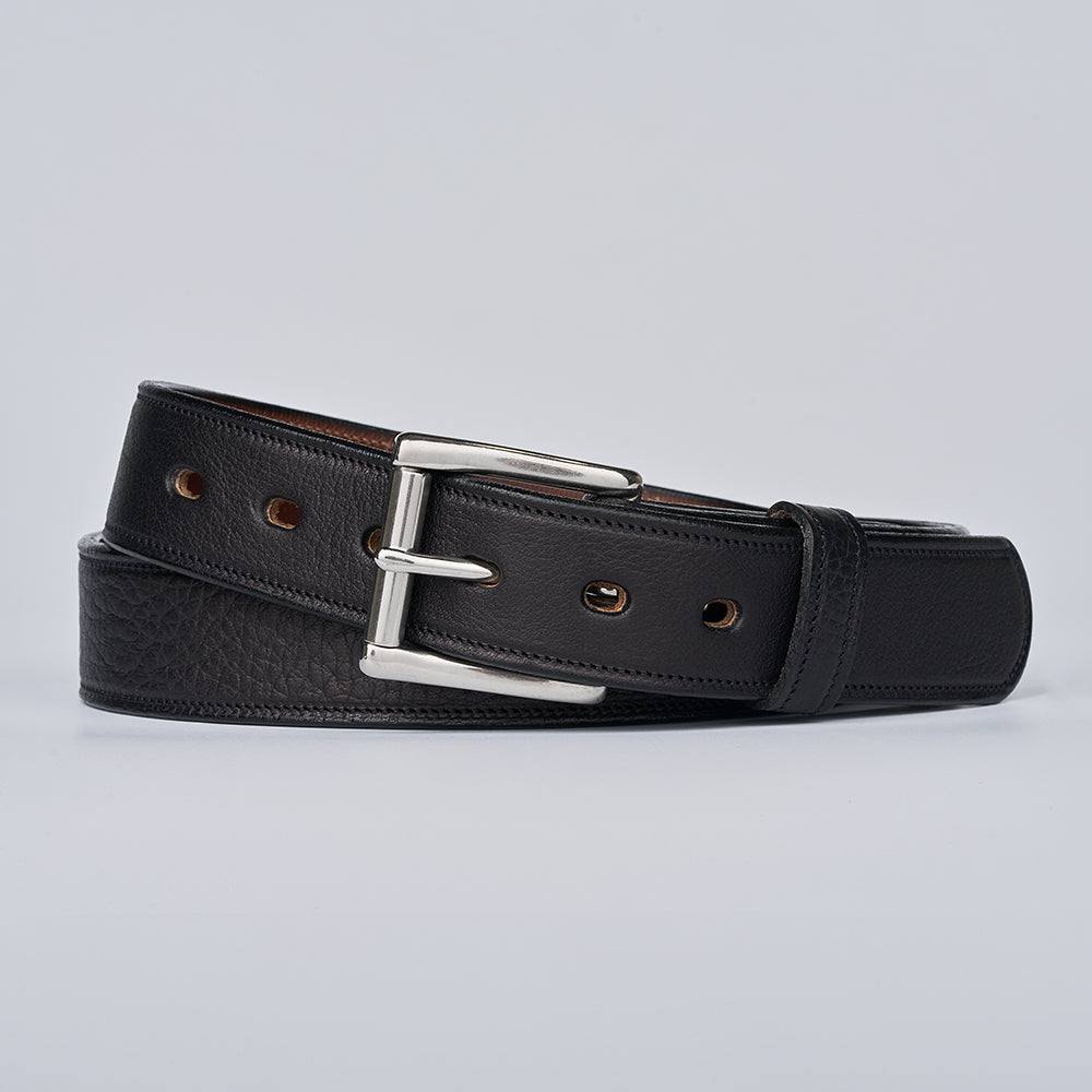Black leather belt with a silver buckle on a light gray background