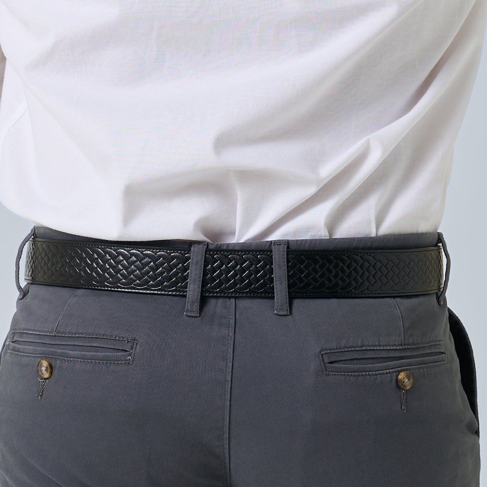 A person is shown from the back wearing a white shirt tucked into gray pants with two buttoned back pockets, paired with Hanks Belts&#39; The Classic Basket Weave black leather belt.