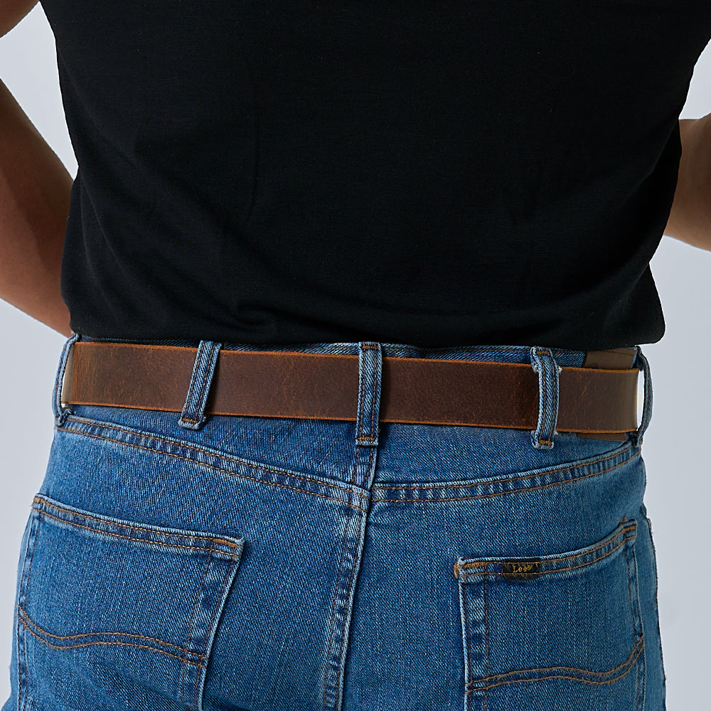 Person wearing a black shirt tucked into blue jeans with The Crazy Horse leather belt by Hanks Belts, shown from the back against a plain background.