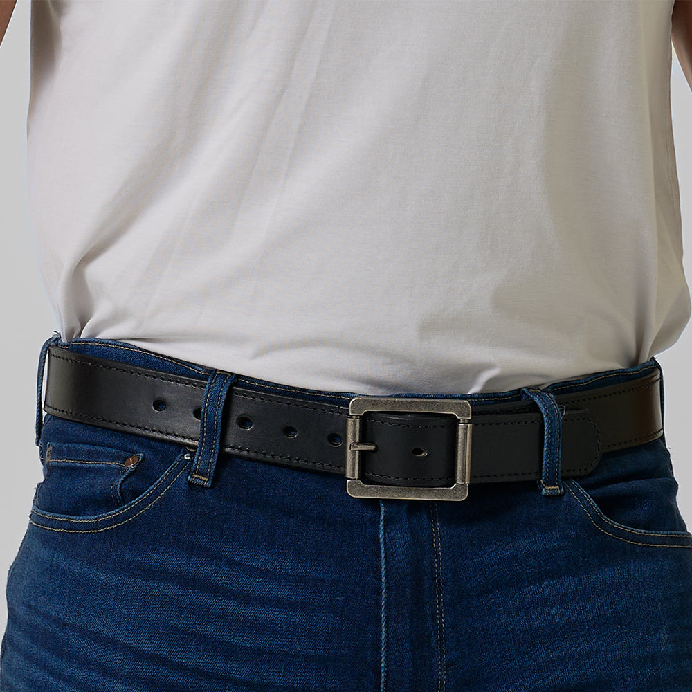 A person wears a white t-shirt tucked into blue jeans, accented with Hanks Belts&#39; The Double Roller—a black belt with a silver rectangular buckle.