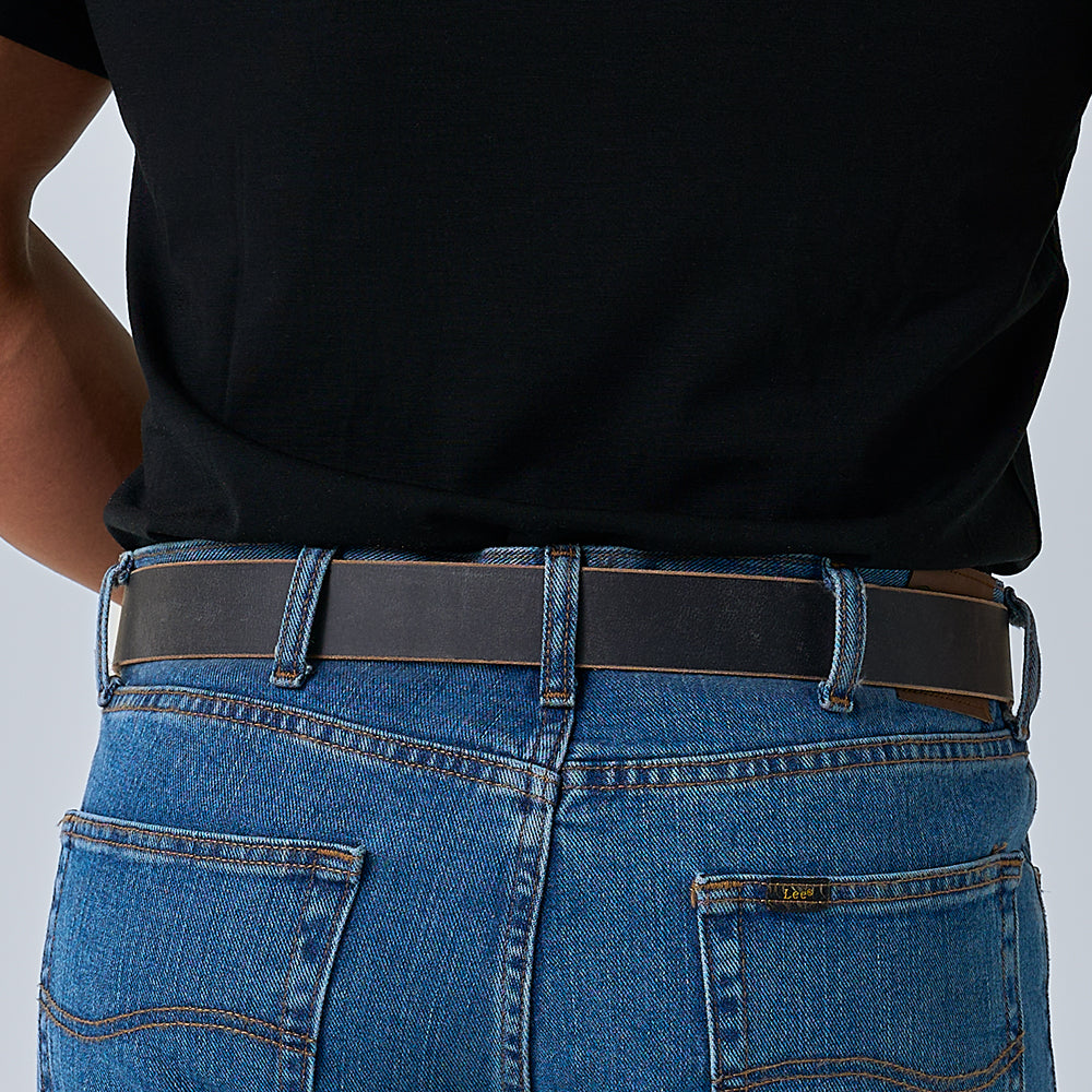 Male model wearing jeans and a black shirt with a Hanks Glacier grey belt, turned around showing the back of the belt.