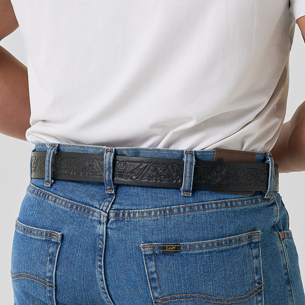 A person in blue jeans and a white t-shirt is shown from the back, wearing the Hanks Belts Gunner Eagle full-grain leather CCW belt. One hand rests on their hip while a card peeks out of the back pocket.