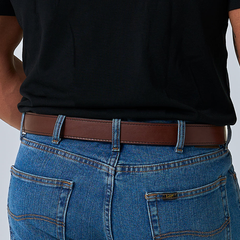 A person is shown from the back, wearing a black t-shirt, blue jeans, and The Kydex Reinforced concealed carry belt by Hanks Belts, with focus on the waist and hip area.