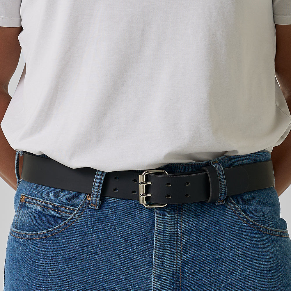A person wears a white shirt tucked into blue jeans, finished with Hanks Belts&#39; The Legend Double Prong Retro Style leather belt and silver buckle.