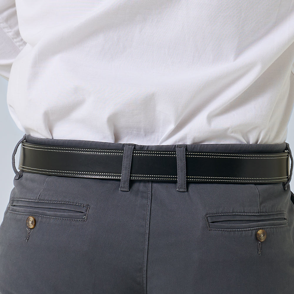 A person wears gray pants and a white shirt tucked in, showcasing the back view of The Premier Double Layer belt from Hanks Belts, made of vegetable-tanned leather with white stitching and visible pants pockets.
