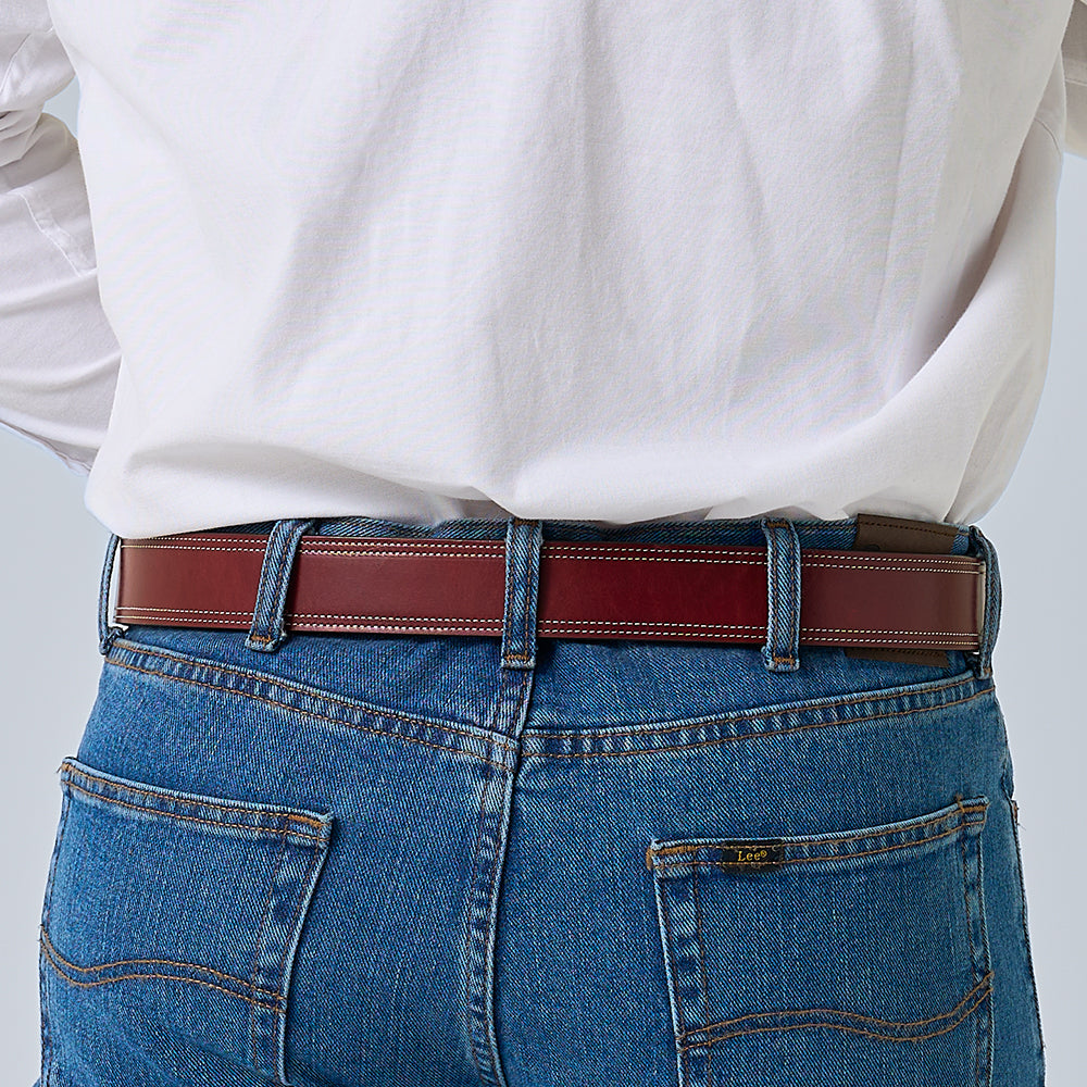 A person in a white shirt tucked into blue jeans with visible pocket stitching, shown from the back, is wearing Hanks Belts&#39; The Premier Double Layer, an English bridle belt crafted from rich vegetable tanned leather.