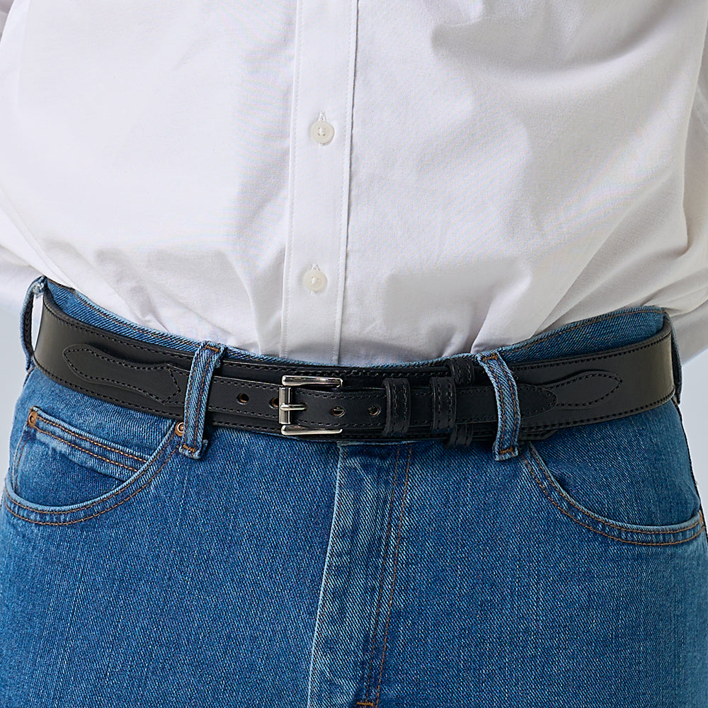 A person wears a white shirt tucked into blue jeans, finished with Hanks Belts&#39; The Ranger—a full-grain leather belt featuring a silver buckle.