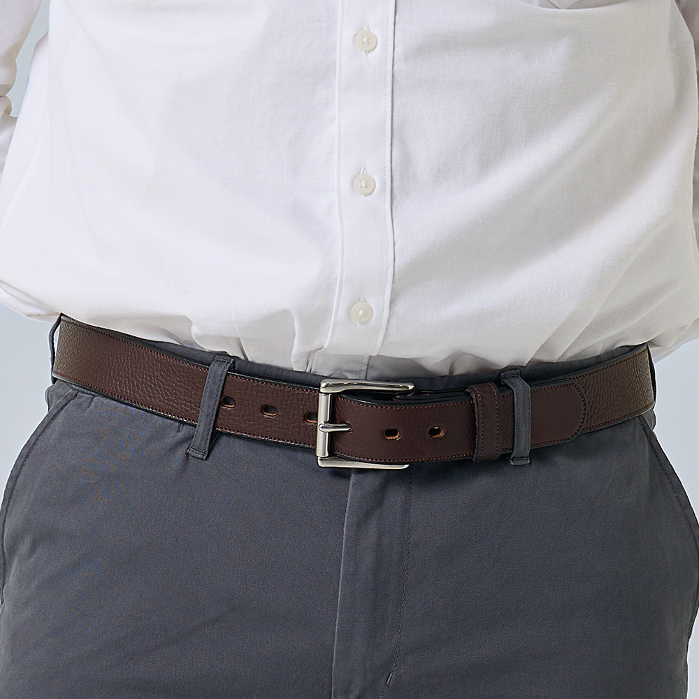 Brown belt worn with a white shirt and gray pants on a light gray background