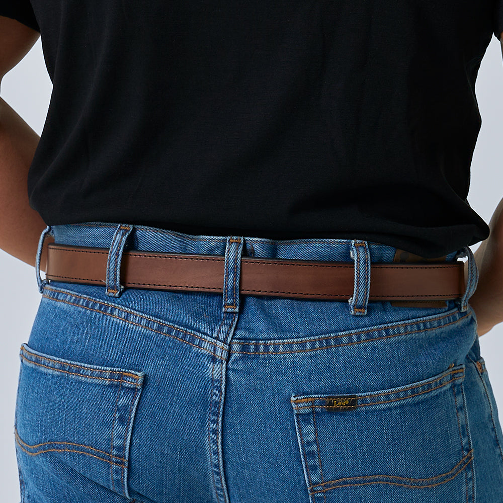 A person wearing a black shirt and blue jeans, shown from the back and waist down, sports The Xtreme - 1.25&quot; brown leather belt by Hanks Belts, with hands resting on hips.