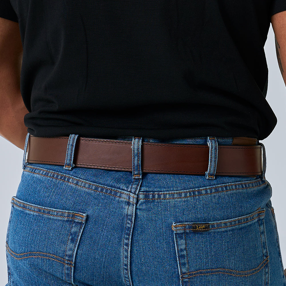 A person is shown from the waist down, back facing the camera, wearing a black shirt, blue jeans, and The Xtreme - 1.75&quot; heavy duty leather work belt by Hanks Belts.