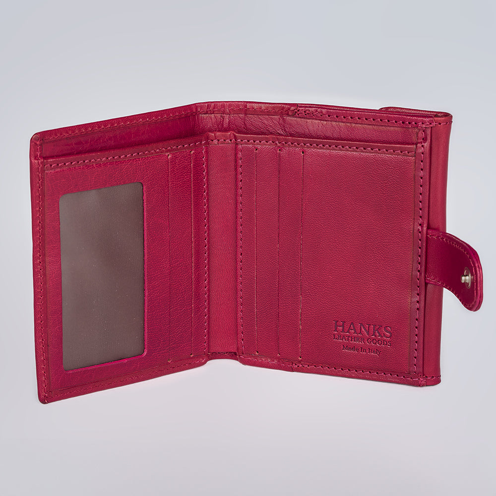 The Adelina Mini Bifold by Hanks Belts is open, showing card slots, a clear ID window, and a snap button. Crafted from full-grain Italian leather and stamped "HANKS BELTS Made in Italy" against a light gray background.