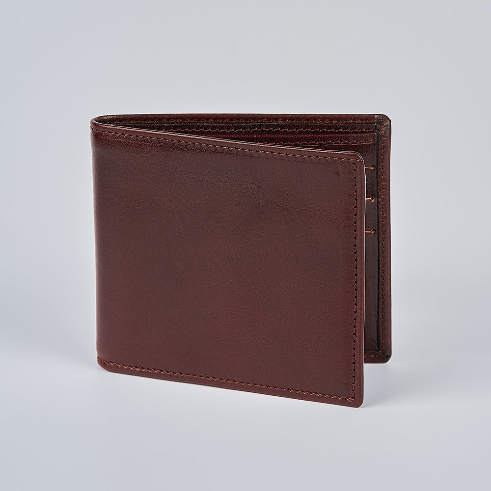 The Hanks Belts Como Italian Bifold wallet stands upright on a light gray background, highlighting its smooth leather surface and clean stitching.