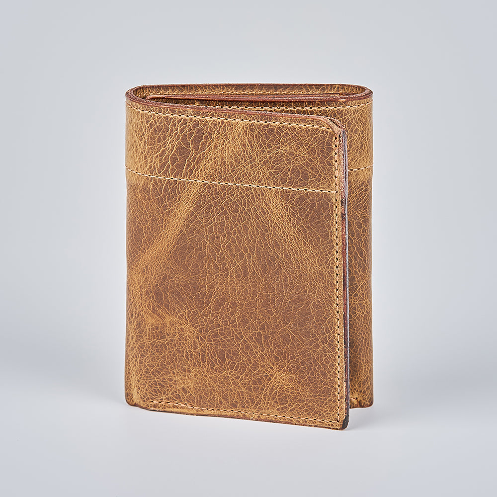 The Hanks Belts Fontana Bison Trifold wallet, handcrafted in the USA from bison leather, stands upright on a light gray background, displaying its textured grain and detailed edge stitching.