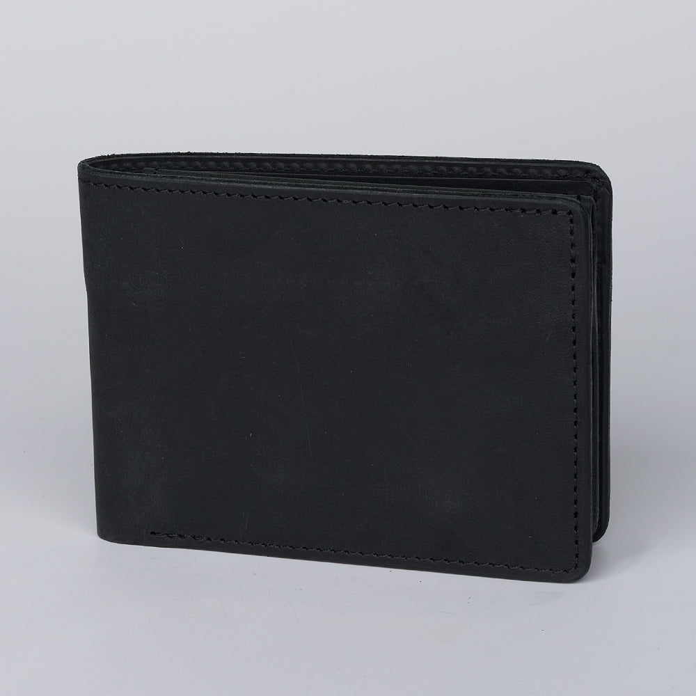 The Hanks Belts Huron Premium Bifold with ID Window, made of black steerhide leather, stands closed and upright on a plain light gray background.