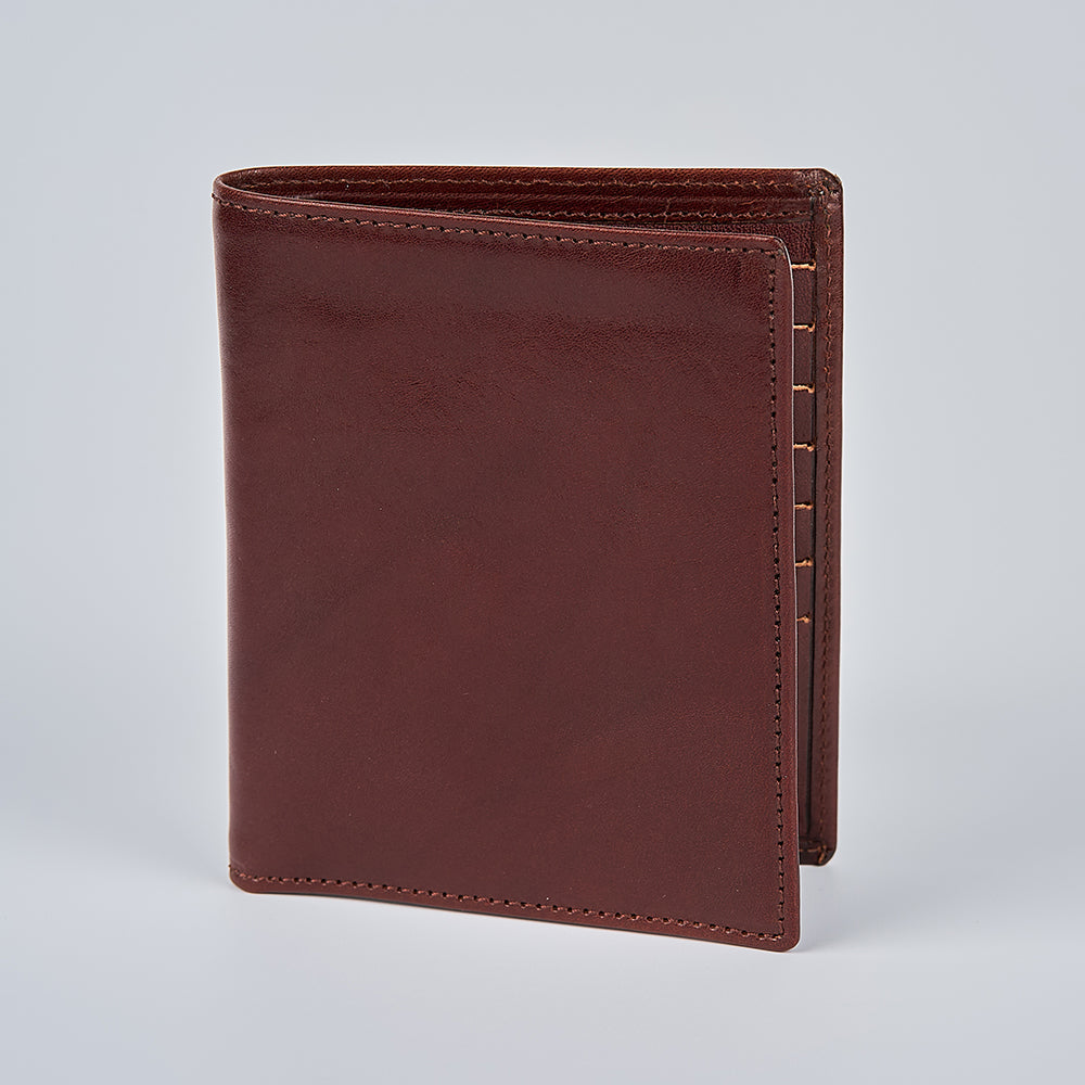 The Hanks Belts Iseo Italian Hipster Bifold, a closed brown full-grain leather wallet, stands upright on a plain light gray background.