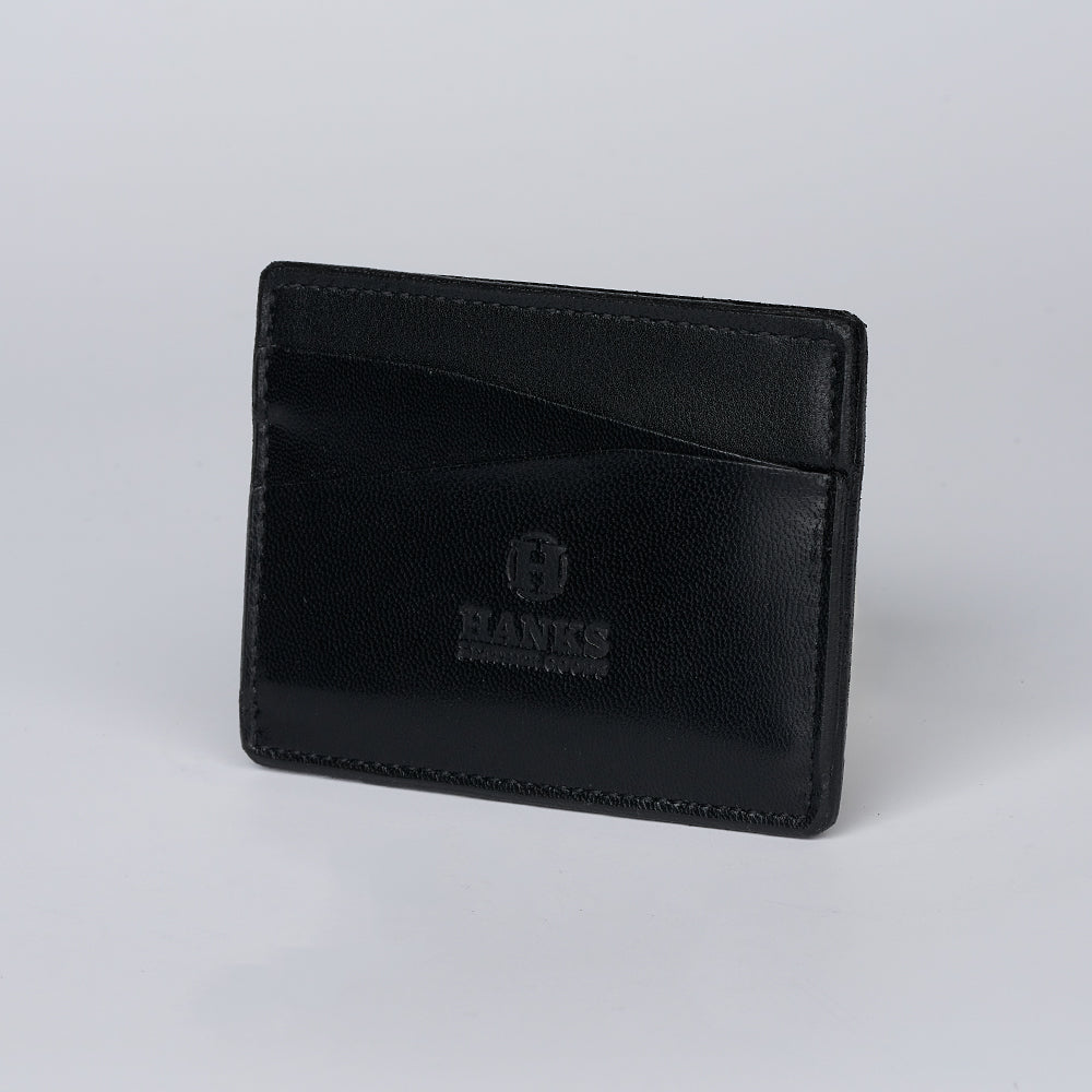 The Monroe Goatskin Card Holder by Hanks Belts is a black wallet with two visible card slots and &quot;HANKS&quot; embossed on the front, displayed upright against a plain light background.