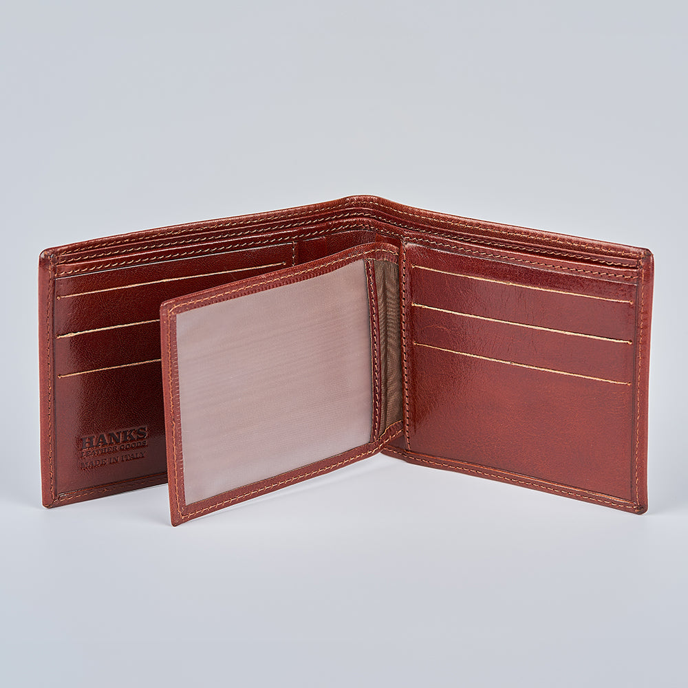 The Orta Italian Bifold with ID Window by Hanks Belts is open, revealing multiple card slots, a flip-over ID compartment, and "Hanks Belts" embossed on the tan interior with gold accent stitching for refined craftsmanship.