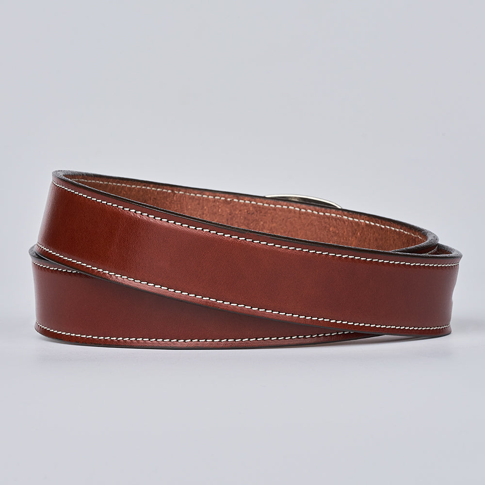 The Eloise by Hanks Belts: a coiled brown women&#39;s belt with white edge stitching, made from vegetable-tanned leather, shown on a plain light gray background.