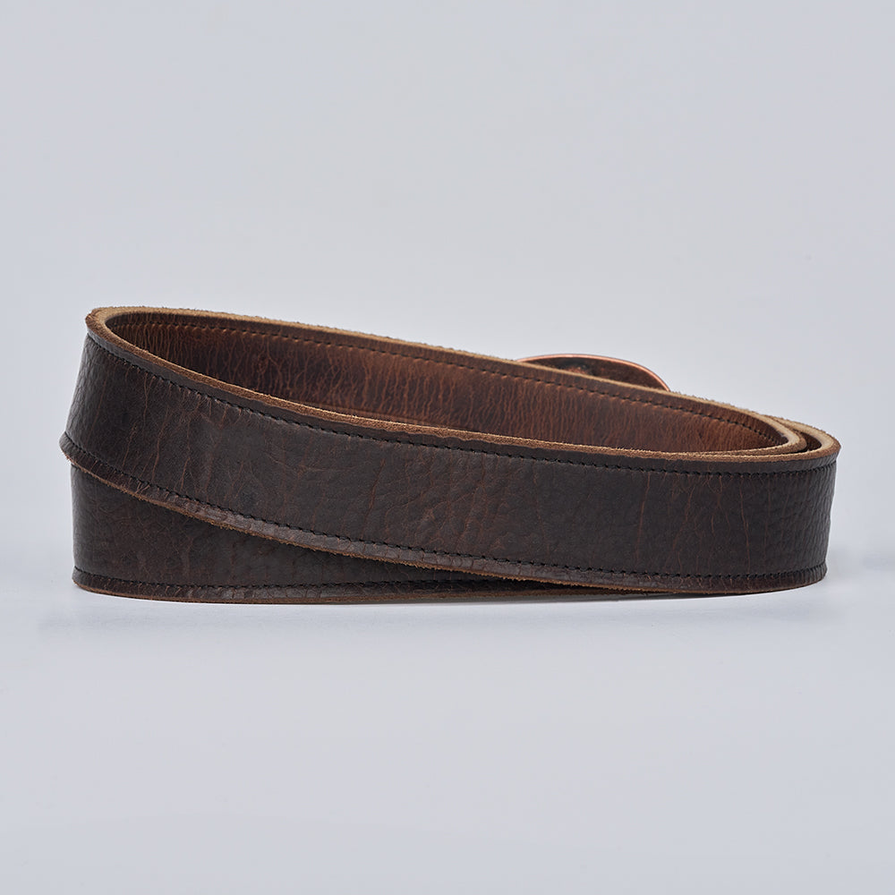 The Hanks Belts Ember - 1.25&quot; is a rolled, dark brown leather belt with a textured surface, shown on a plain light background.