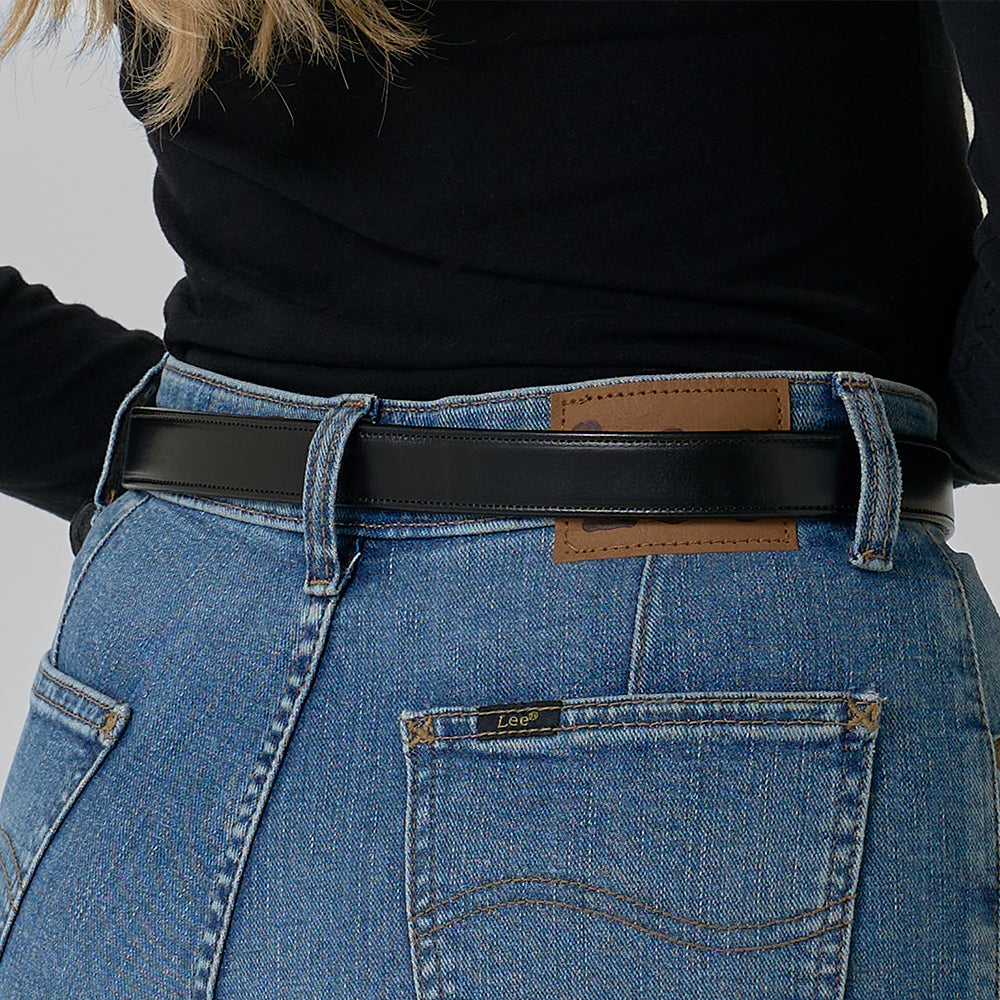 A person shown from the back waist down wears blue Lee jeans with a brown patch, a black long-sleeve top, and the Addyson - 1&quot; black belt by Hanks Belts with a brass buckle.