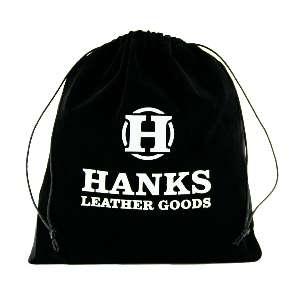 The Hanks Premium Velvet Gift Bag, in black velvet with a double cord drawstring, displays &quot;Hanks Belts&quot; in white alongside a stylized &quot;H.