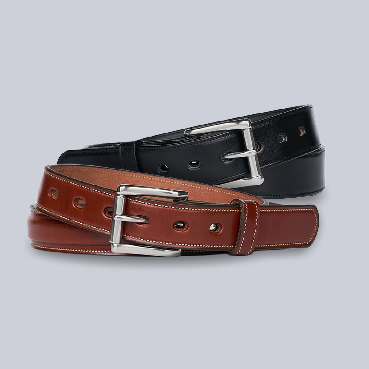The Esquire and The Canyon leather belts from Hanks Belts—one black, one brown—are stacked together. Both feature silver rectangular buckles, visible edge stitching, and large round holes, set against a plain light gray background.