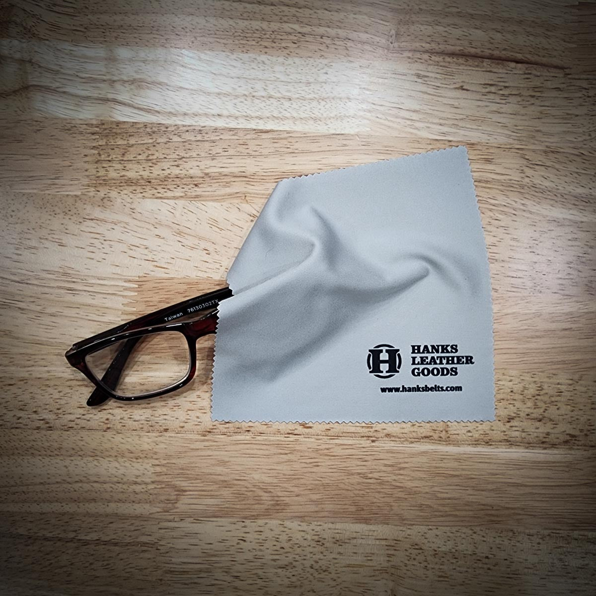 2 Eyeglass Cleaning Cloths on wood table 