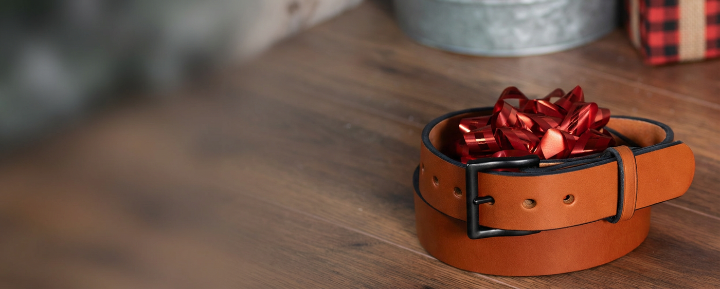 Brown leather belt with a red bow on a wooden surface