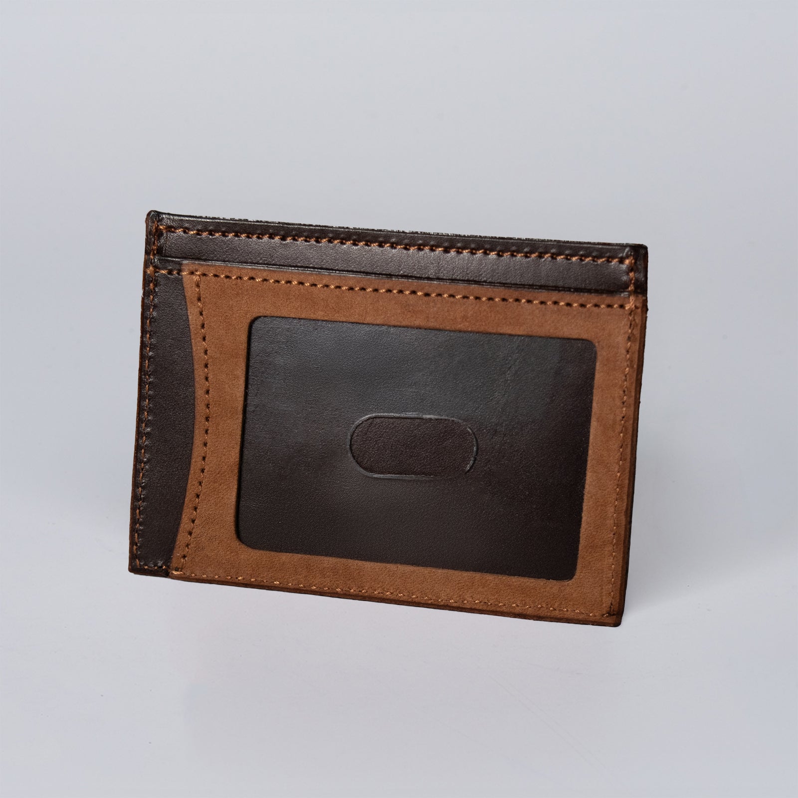 The Hanks Belts Whiskeytown Cardholder in chocolate brown stands upright against a plain white background, featuring a transparent ID card slot on one side.
