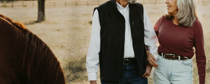 Man and woman standing next to a horse in a rural setting