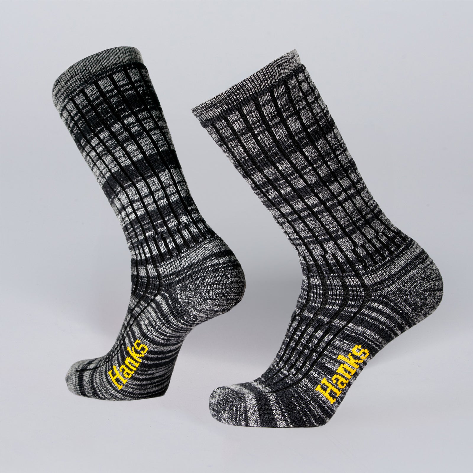 Two black and gray patterned Upland Socks by Hank Belts feature "Hanks" in yellow on the soles, shown against a plain light gray background.