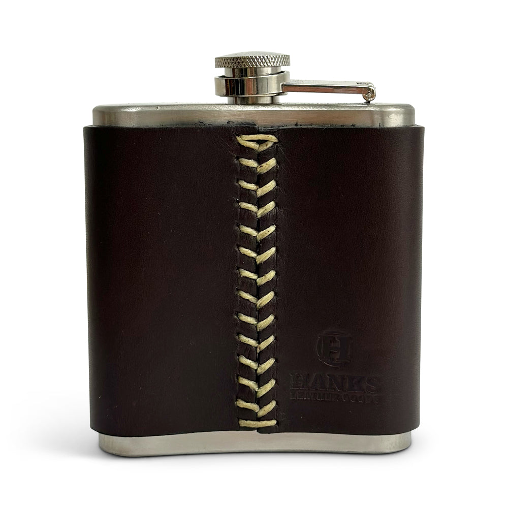 The Leather Covered Flask by Hanks Belts showcases a stainless steel construction wrapped in USA-tanned leather, adorned with a striking light-colored cross-stitched pattern. The leather is embossed with &quot;HANKS PARKER GOODS&quot; near the bottom right corner.