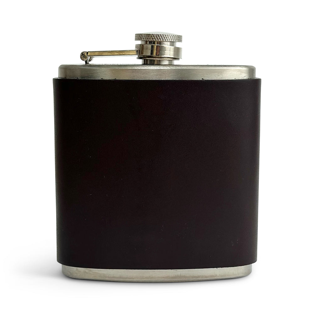 The Leather Covered Flask by Hanks Belts features a Havana color and an elegant design. It is wrapped in USA Tanned leather around the stainless steel body, with a screw-on cap attached via a hinge to ensure it remains connected. The overall look is sleek and minimalist, making it perfect for discreetly carrying alcoholic beverages.